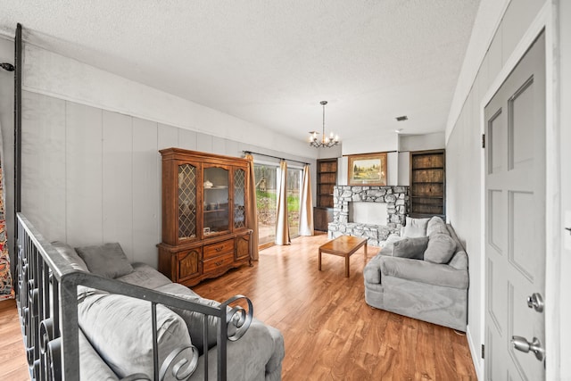 living room featuring light wood finished floors, a textured ceiling, and a notable chandelier