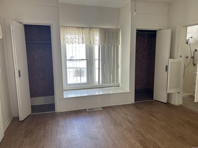 unfurnished bedroom featuring wood finished floors, visible vents, and a closet