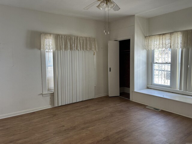 spare room with a ceiling fan, visible vents, and wood finished floors