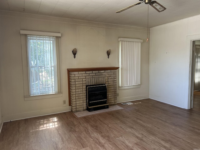 unfurnished living room featuring a wealth of natural light, wood finished floors, a ceiling fan, and ornamental molding