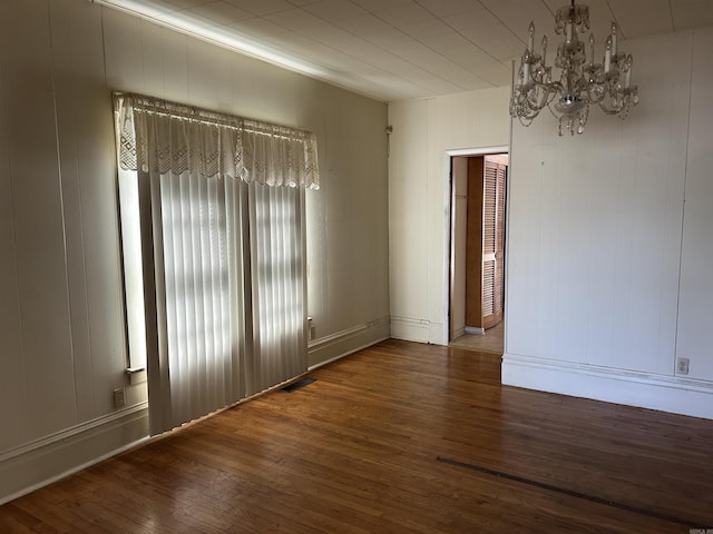 unfurnished room with visible vents, hardwood / wood-style flooring, and a notable chandelier