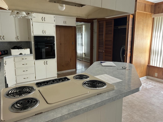 kitchen with stove, light floors, white cabinetry, oven, and baseboards