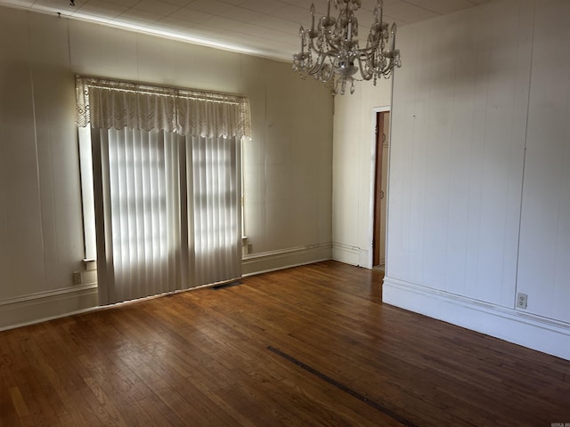 unfurnished room with an inviting chandelier and wood finished floors