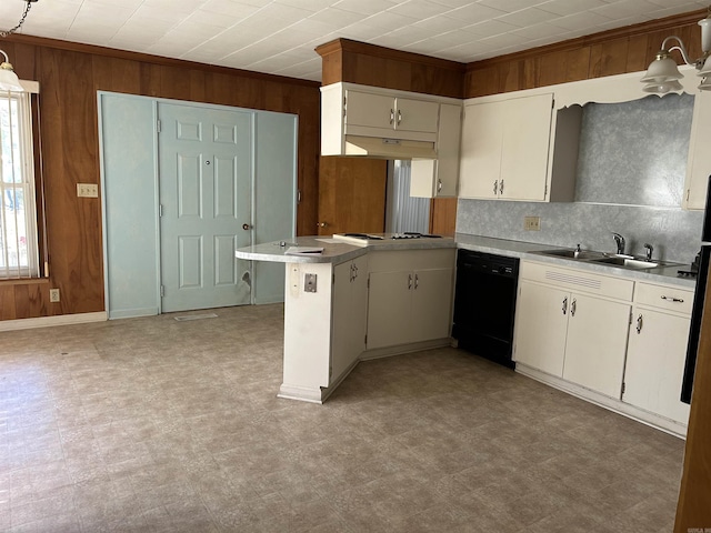 kitchen with a sink, wood walls, dishwasher, light floors, and a peninsula