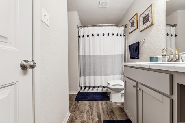 full bathroom with visible vents, a textured wall, toilet, wood finished floors, and vanity