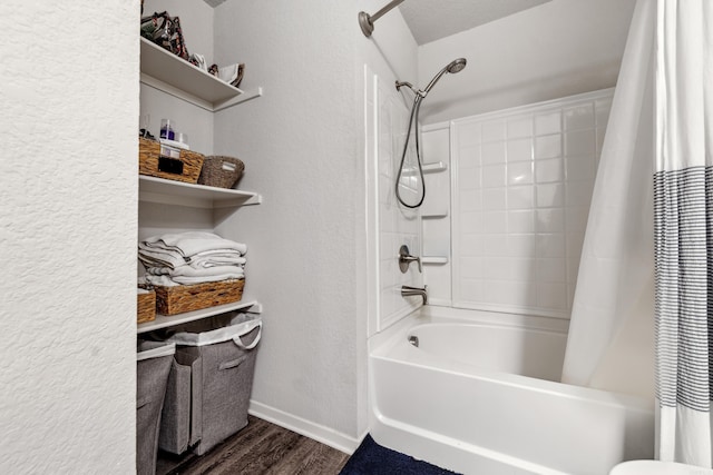 bathroom with shower / bath combo, a textured wall, wood finished floors, and baseboards