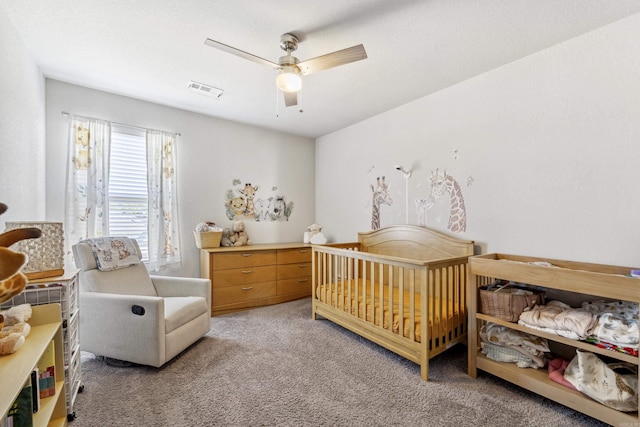 bedroom featuring light colored carpet, visible vents, a ceiling fan, and a nursery area