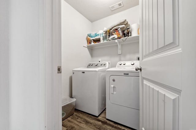 washroom with dark wood-style floors, visible vents, washer and dryer, and laundry area