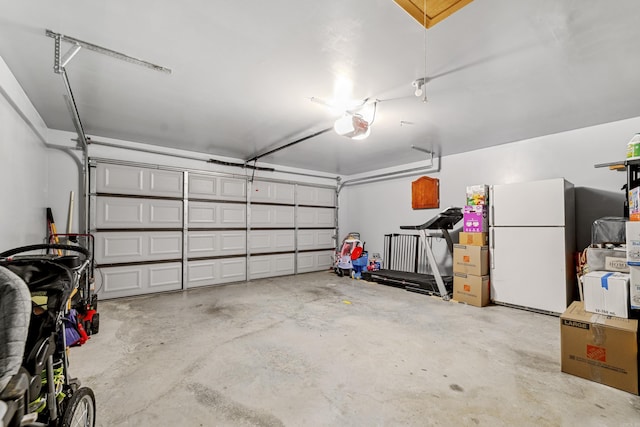 garage with a garage door opener and freestanding refrigerator