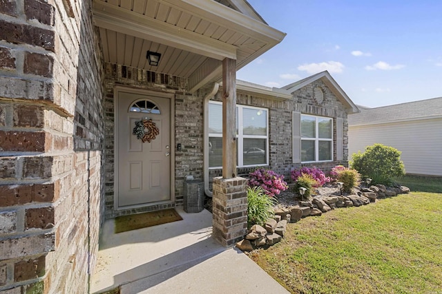 entrance to property featuring a lawn and brick siding