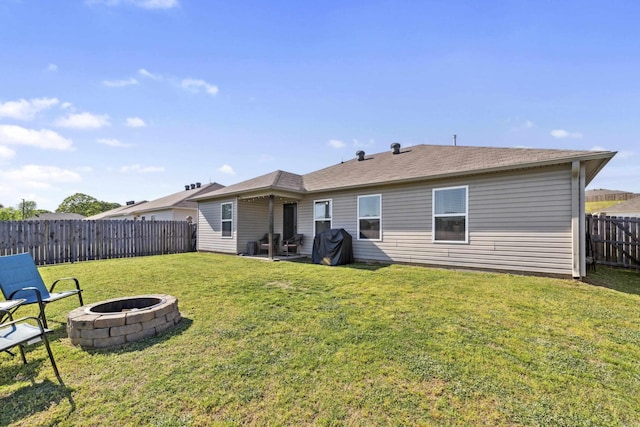 rear view of property featuring a fire pit, a fenced backyard, and a yard