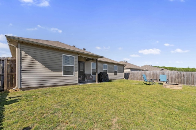 rear view of house featuring a fire pit, a fenced backyard, and a lawn
