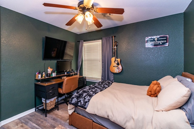 bedroom with ceiling fan, a textured wall, wood finished floors, and baseboards