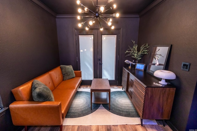 living area with a chandelier, wood finished floors, crown molding, and a textured wall