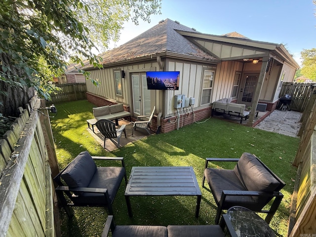 rear view of house featuring board and batten siding, a shingled roof, a patio, an outdoor hangout area, and a lawn