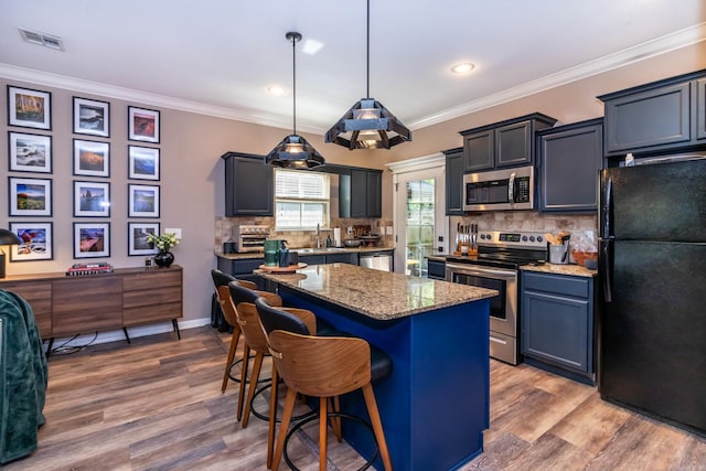 kitchen featuring light stone countertops, a breakfast bar, appliances with stainless steel finishes, a center island, and visible vents