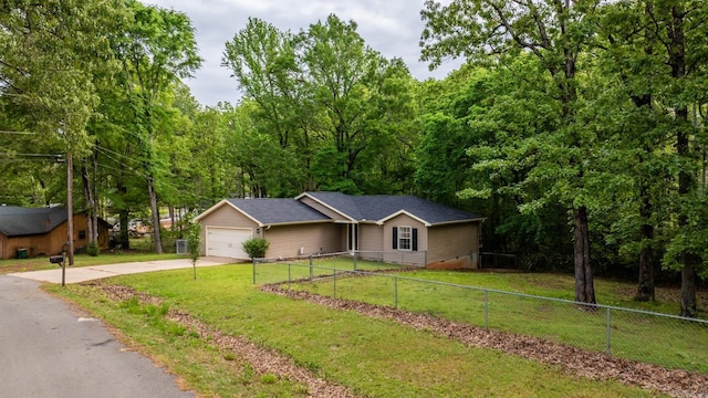 single story home featuring driveway, an attached garage, a front lawn, a view of trees, and fence private yard