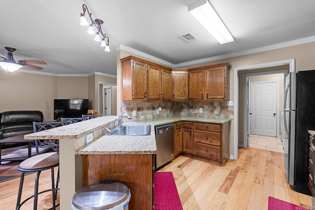 kitchen featuring brown cabinets, a sink, light wood-style floors, visible vents, and appliances with stainless steel finishes