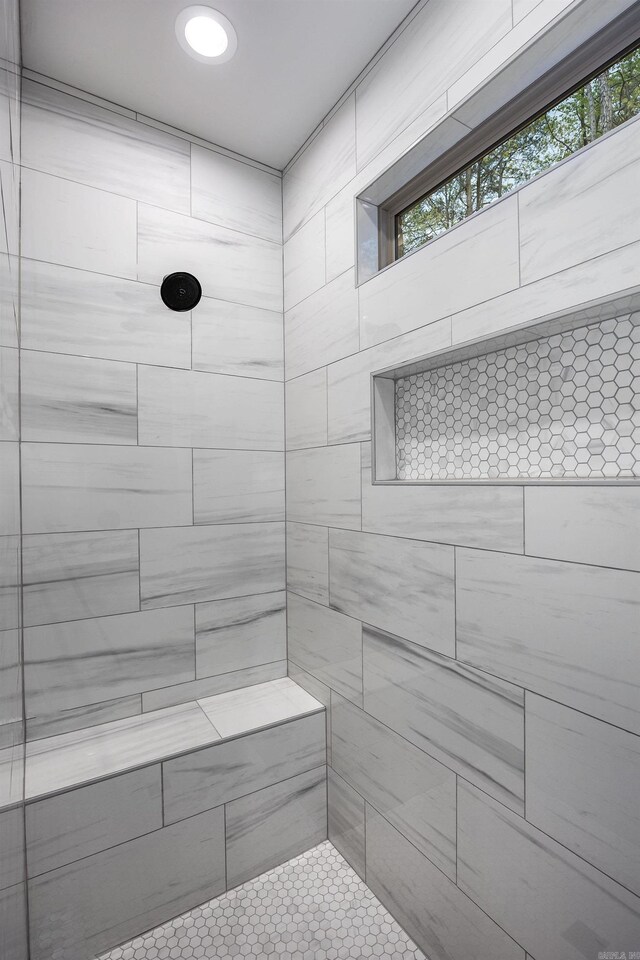 full bathroom with tiled shower and a healthy amount of sunlight