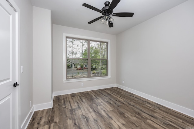 empty room with dark wood-style flooring, a ceiling fan, and baseboards
