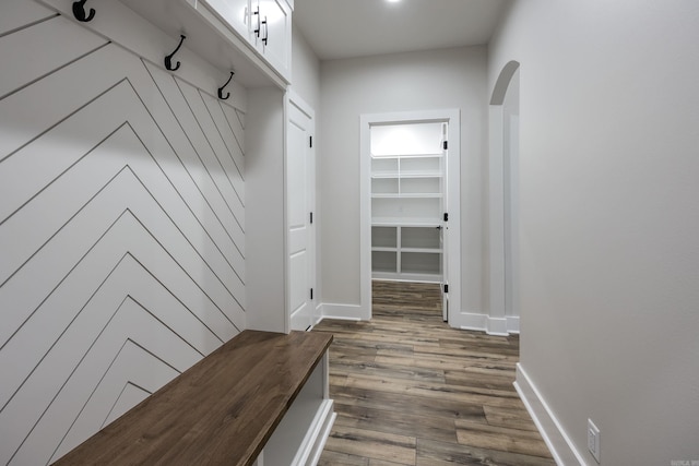 mudroom with baseboards, arched walkways, and dark wood-type flooring
