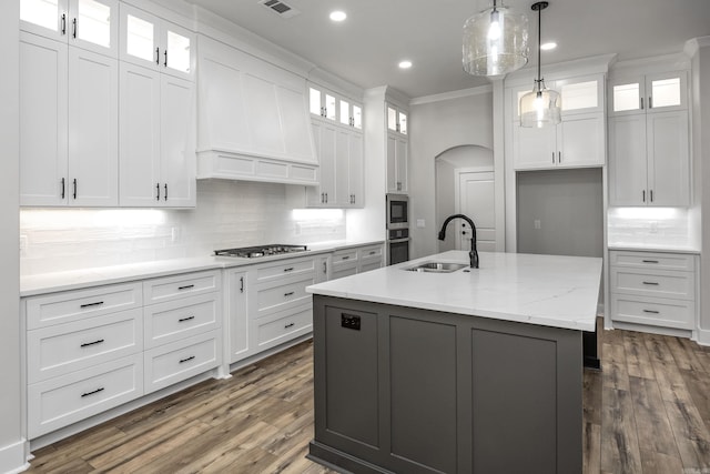 kitchen featuring tasteful backsplash, crown molding, a sink, appliances with stainless steel finishes, and arched walkways