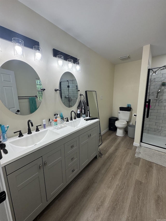 bathroom featuring toilet, a sink, wood finished floors, and visible vents