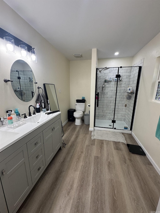 full bathroom with a sink, a shower stall, toilet, visible vents, and wood finished floors