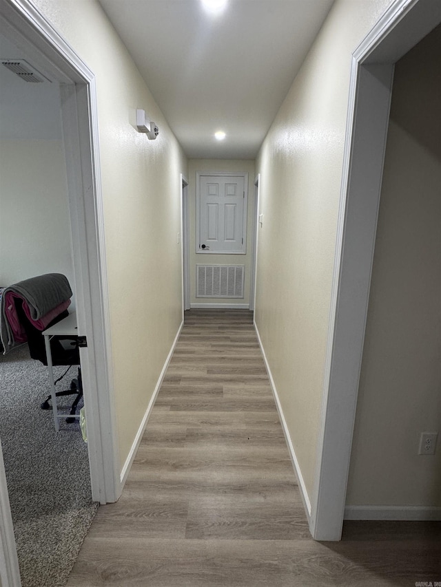 hall with visible vents, light wood-type flooring, and baseboards