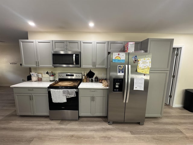 kitchen with stainless steel appliances, light wood finished floors, and gray cabinets