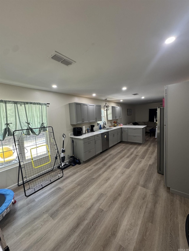 kitchen with stainless steel appliances, light wood-style floors, light countertops, gray cabinetry, and visible vents