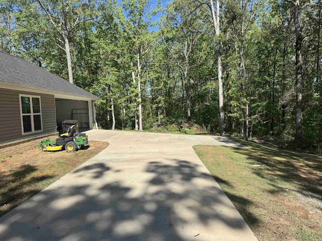 view of patio / terrace with driveway and a view of trees
