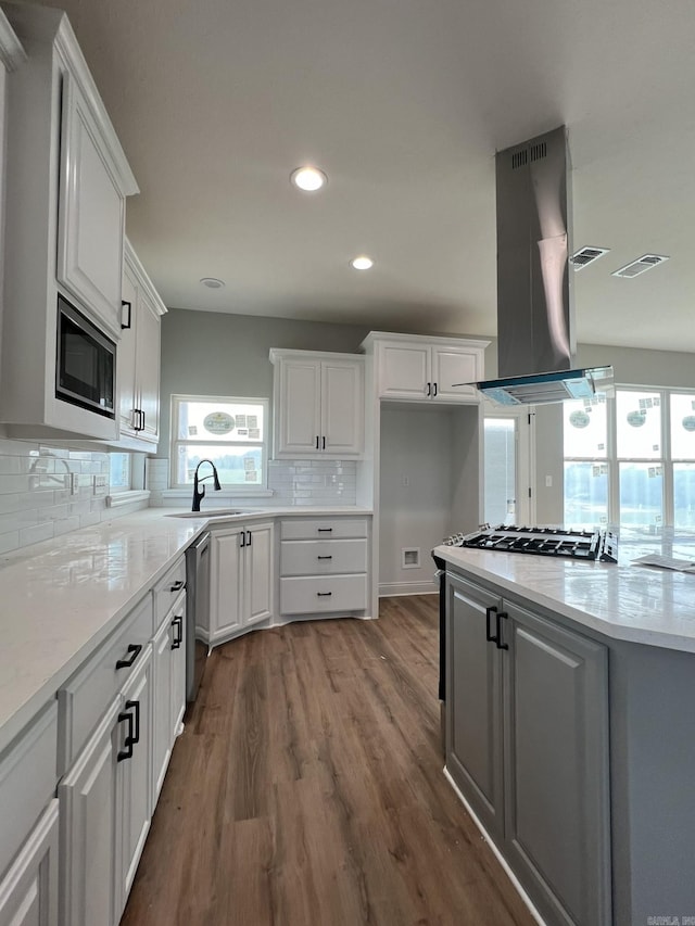 4406 Magee Dr, Texarkana, AR 71854 - kitchen with white cabinets, island range hood, stainless steel appliances, and plenty of natural light