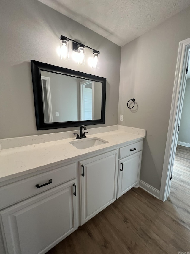 4406 Magee Dr, Texarkana, AR 71854 - bathroom featuring a textured ceiling, wood finished floors, vanity, and baseboards