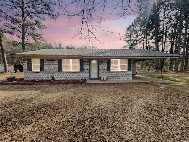 ranch-style house with brick siding, metal roof, and an attached carport