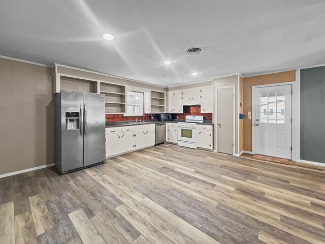 kitchen featuring open shelves, dark countertops, light wood-style floors, and appliances with stainless steel finishes