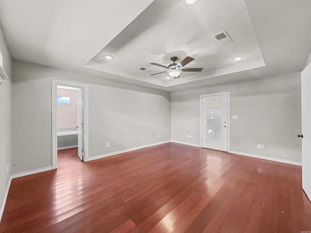 spare room with visible vents, wood finished floors, a ceiling fan, and a tray ceiling