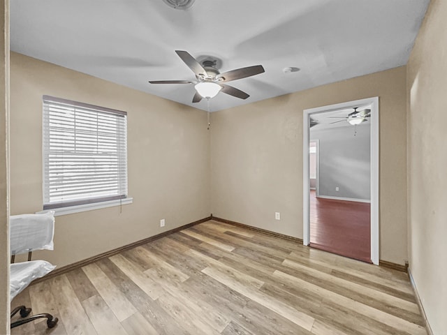 unfurnished room featuring a ceiling fan, baseboards, and light wood-type flooring