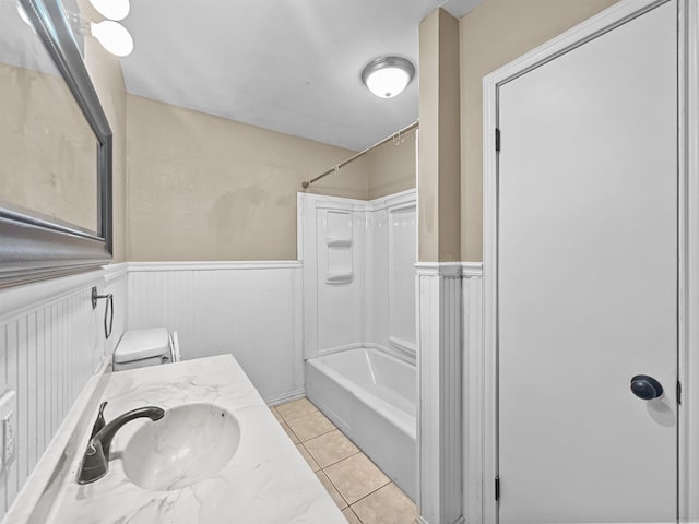 full bathroom with tile patterned floors, wainscoting, washtub / shower combination, and toilet