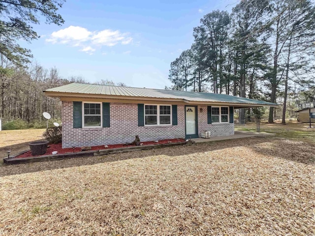 single story home with metal roof, an attached carport, and brick siding