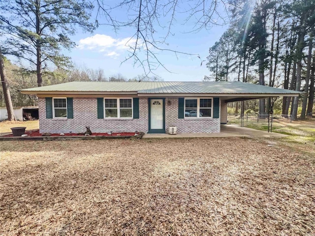 ranch-style home with metal roof, a carport, and brick siding