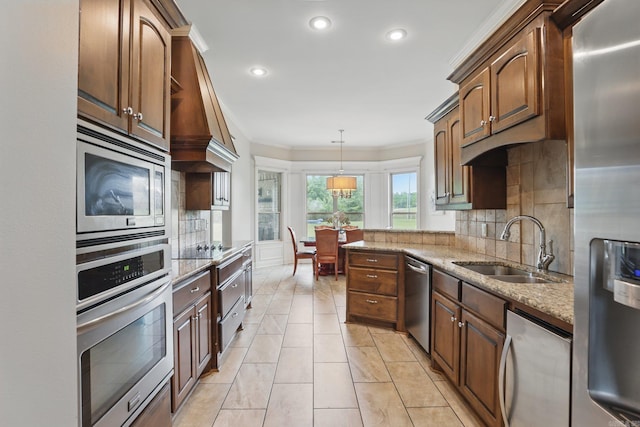 kitchen with light stone countertops, ornamental molding, appliances with stainless steel finishes, and a sink