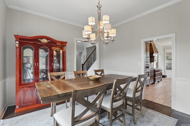 dining room with stairway, wood finished floors, an inviting chandelier, and crown molding