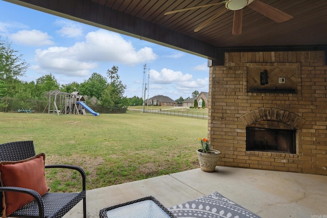 view of yard featuring a patio area, ceiling fan, a fenced backyard, a playground, and an outdoor brick fireplace