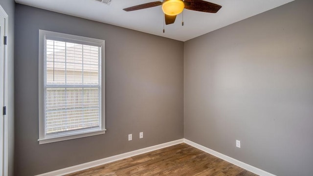 unfurnished room with dark wood finished floors, a ceiling fan, visible vents, and baseboards
