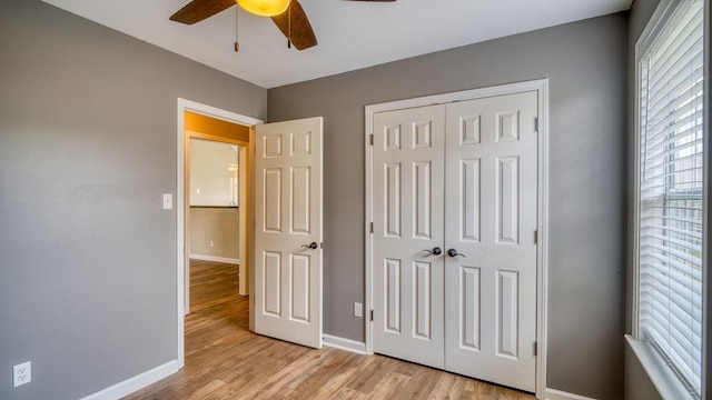 unfurnished bedroom featuring baseboards, a ceiling fan, light wood-style floors, and a closet