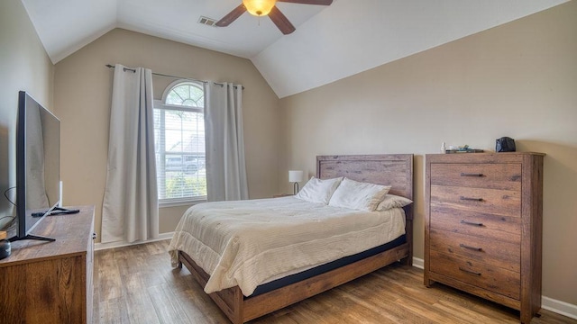 bedroom with ceiling fan, visible vents, baseboards, vaulted ceiling, and wood finished floors