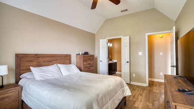 bedroom featuring wood finished floors, vaulted ceiling, ensuite bathroom, baseboards, and visible vents