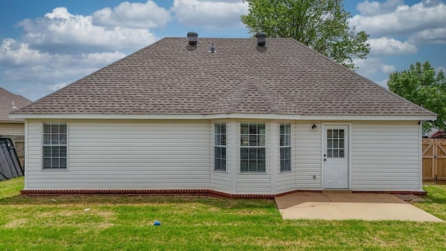 back of property with fence, roof with shingles, a yard, and a patio
