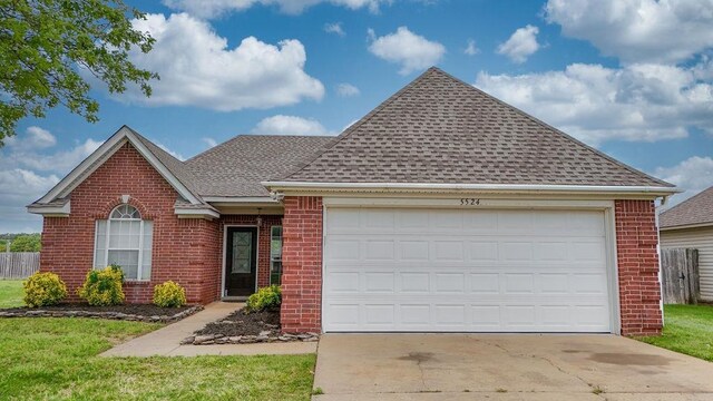 ranch-style home featuring brick siding, fence, a shingled roof, a garage, and concrete driveway